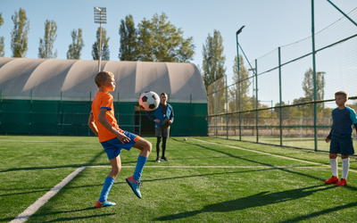 Young boys playing football soccer match at training camp for kids. Sports tournament for youth team at summer