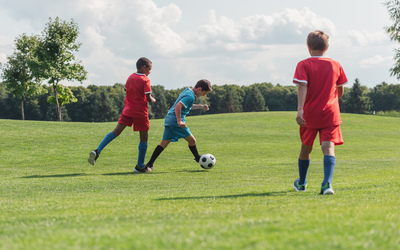 multicultural and cute kids playing football outside